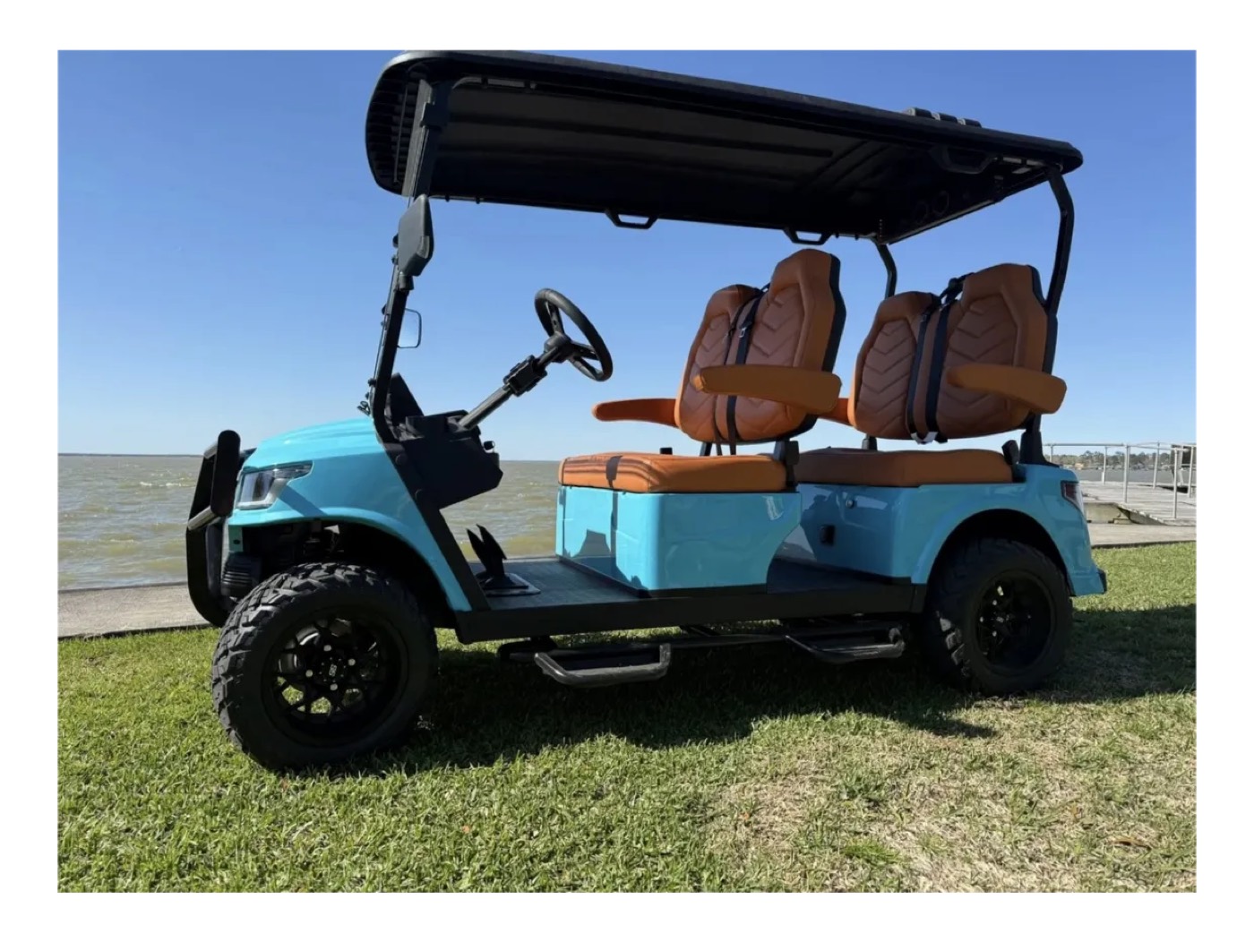 Teal Breezy EV golf cart with quilted leather seats by a lake