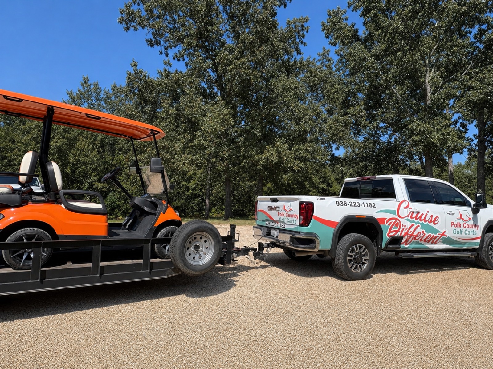 PCGC branded 'Cruise Different' GMC truck hitched to a trailer with an orange Breezy EV cart